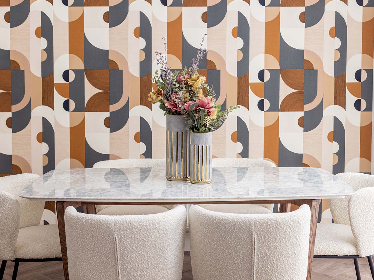 A modern dining room featuring bold geometric wallpaper, a marble-topped table, and chic white boucle dining chairs