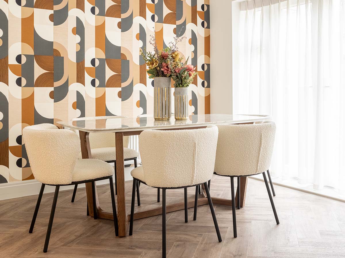 Dining room with geometric wallpaper and white boucle chairs
