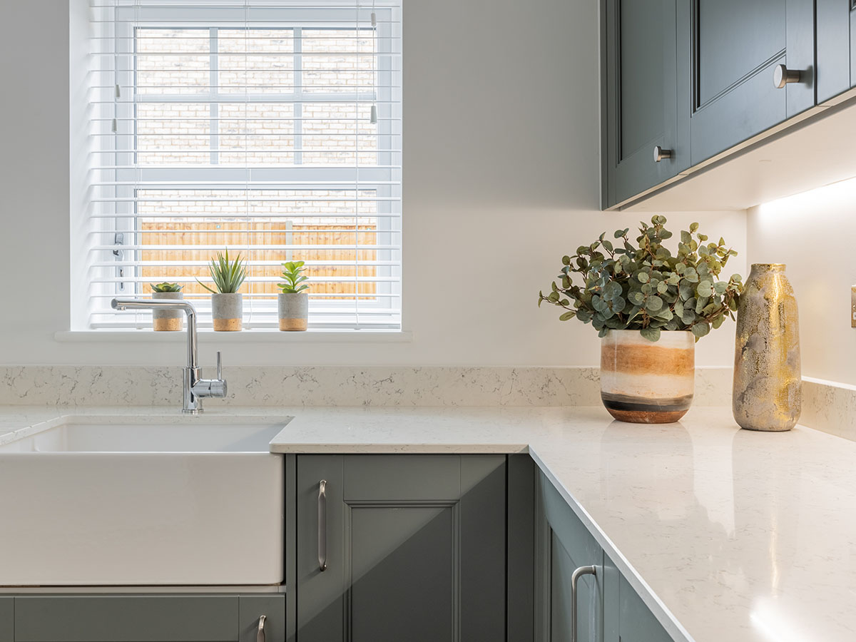 A modern shaker-style kitchen with dark grey cabinets, white quartz countertops, and a large ceramic farmhouse sink