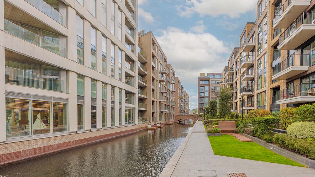 The serene canal at the Chelsea Creek development in London, flanked by modern apartment buildings and landscaped pedestrian walkways