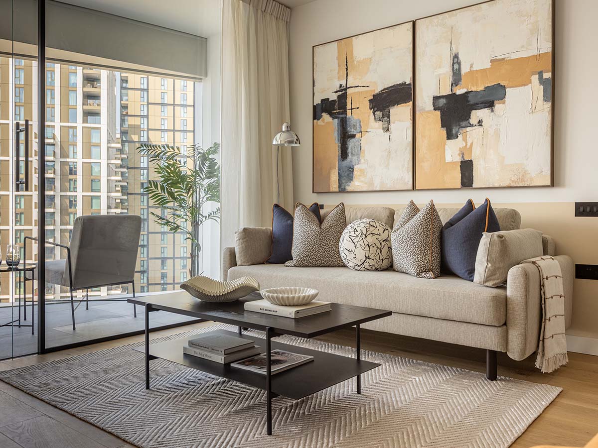 The living room at Koa House, showcasing a beige sofa with navy and leopard-print cushions beneath a large two-panel abstract paintinground-cushion
