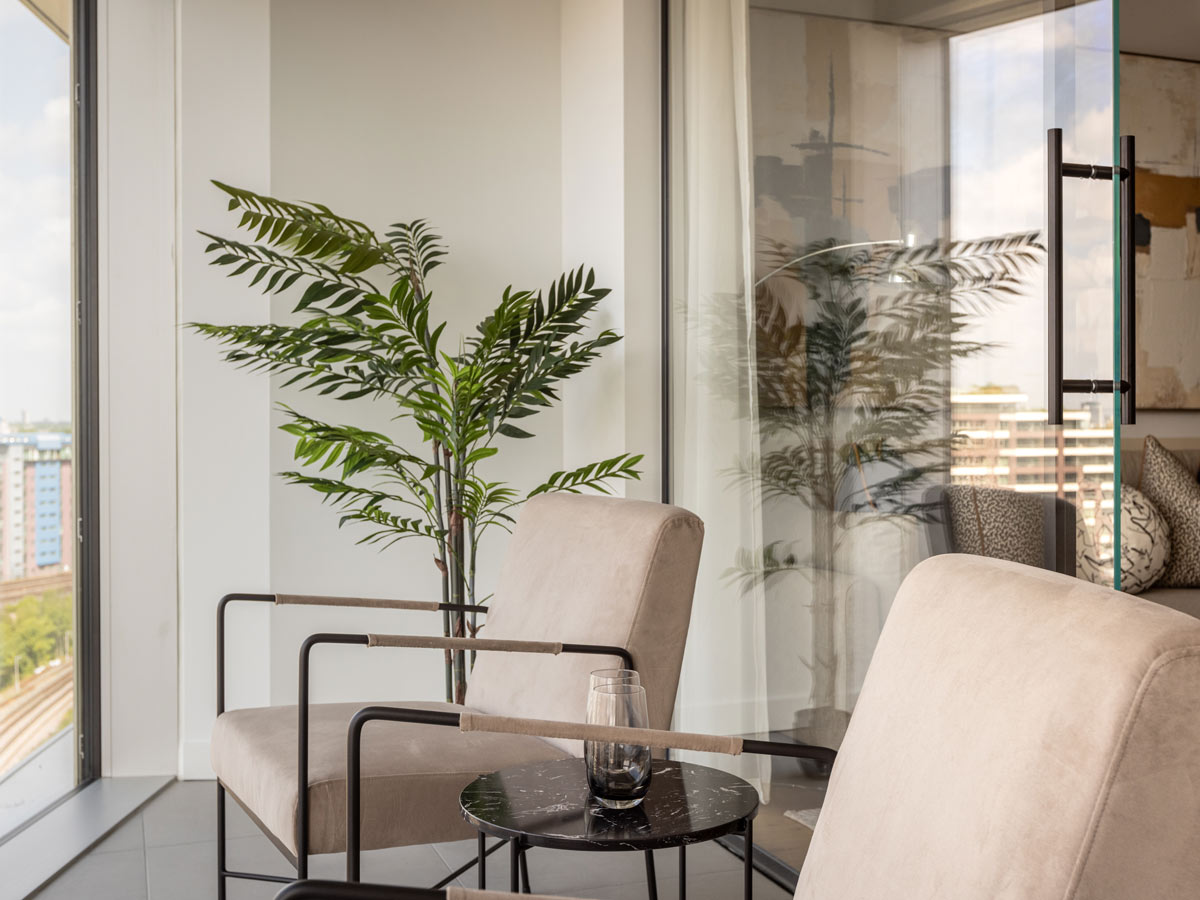 A modern seating area with two armchairs and a tall plant next to a large window at Koa House