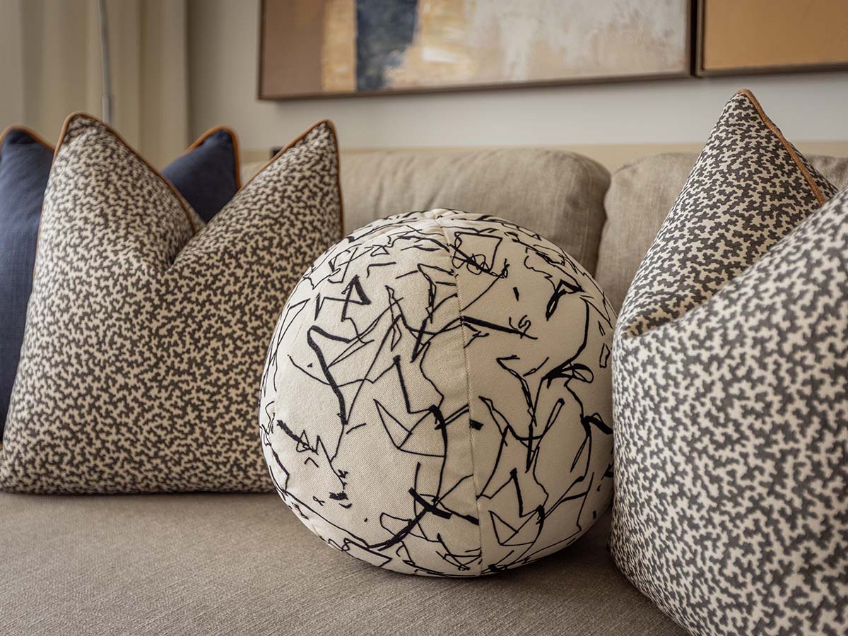 A close-up of decorative cushions on a sofa at Koa House, featuring a unique spherical cushion with a black and white abstract pattern