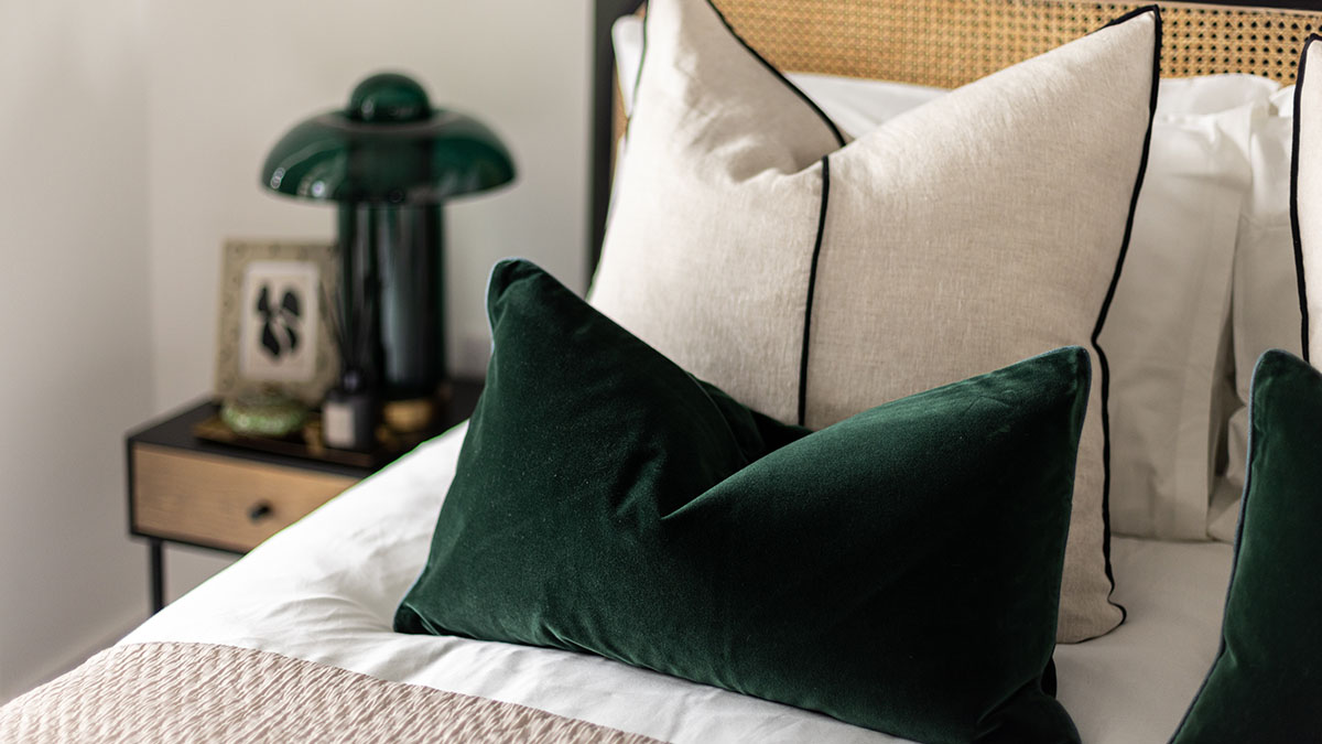 Close-up of a staged bedroom with green velvet pillows, highlighting high-quality furnishings for a London property