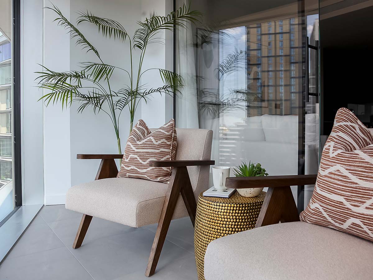 A stylishly furnished winter garden, designed for property investors to maximize rental appeal with modern armchairs and a brass side table