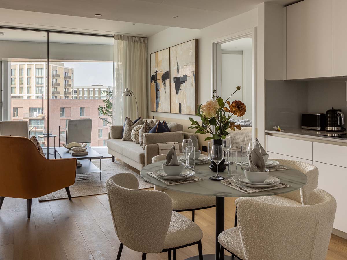 A fully furnished open-plan apartment showcasing a turnkey furniture package for landlords, including a dining set, sofa, and kitchen essentials