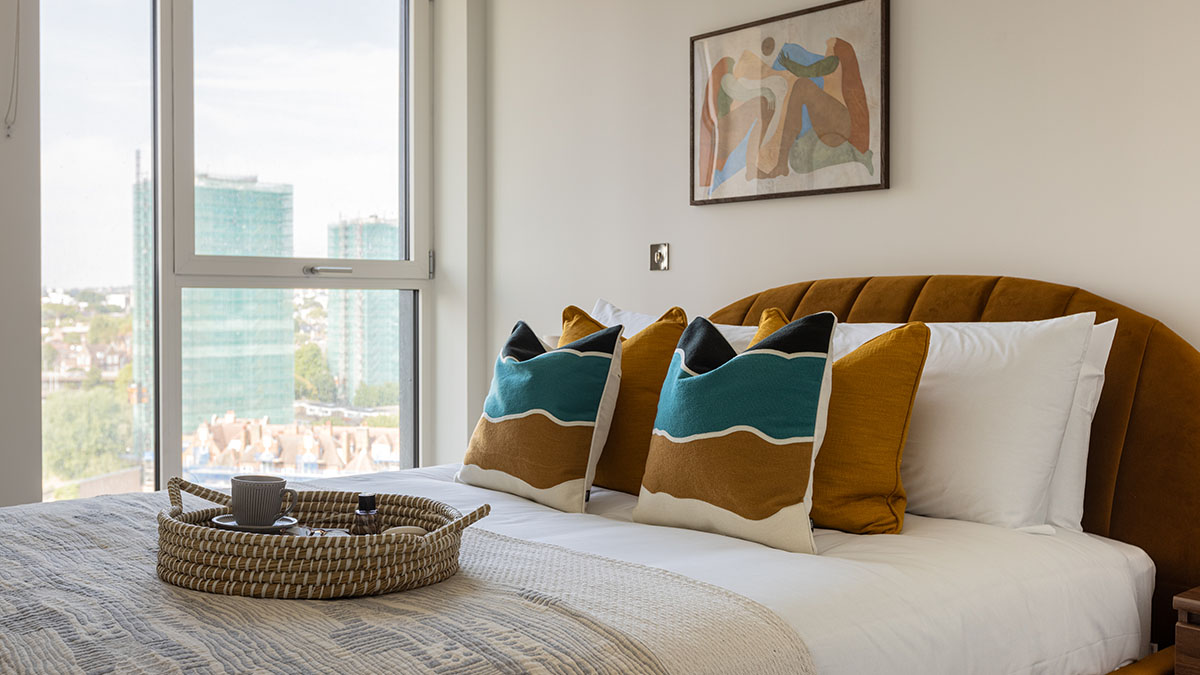 Professionally furnished White City London flat bedroom with elegant bedding and cushions, designed to appeal to renters