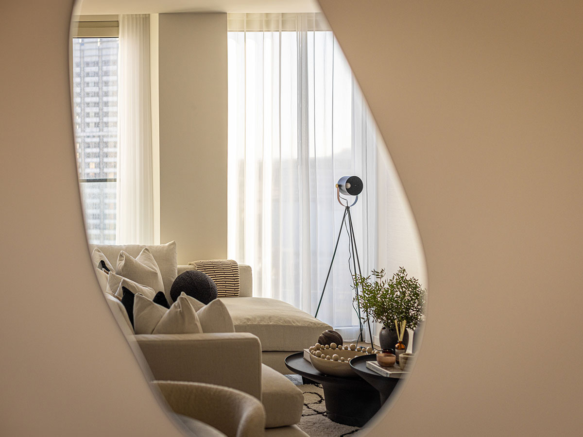 An artistic view into a modern living room at Southbank Tower, seen through the reflection in an organically shaped mirror