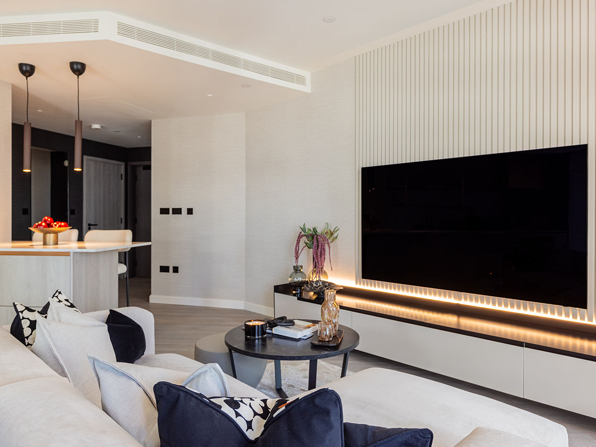 The living room at the Aspen project, focusing on a bespoke media unit with a backlit, slatted feature wall and a large L-shaped sofa