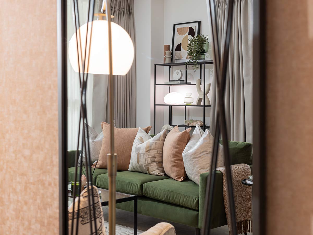 A creative shot showing the reflection of a stylishly decorated living room with a green sofa in a large mirror at the Verdica, Camden project