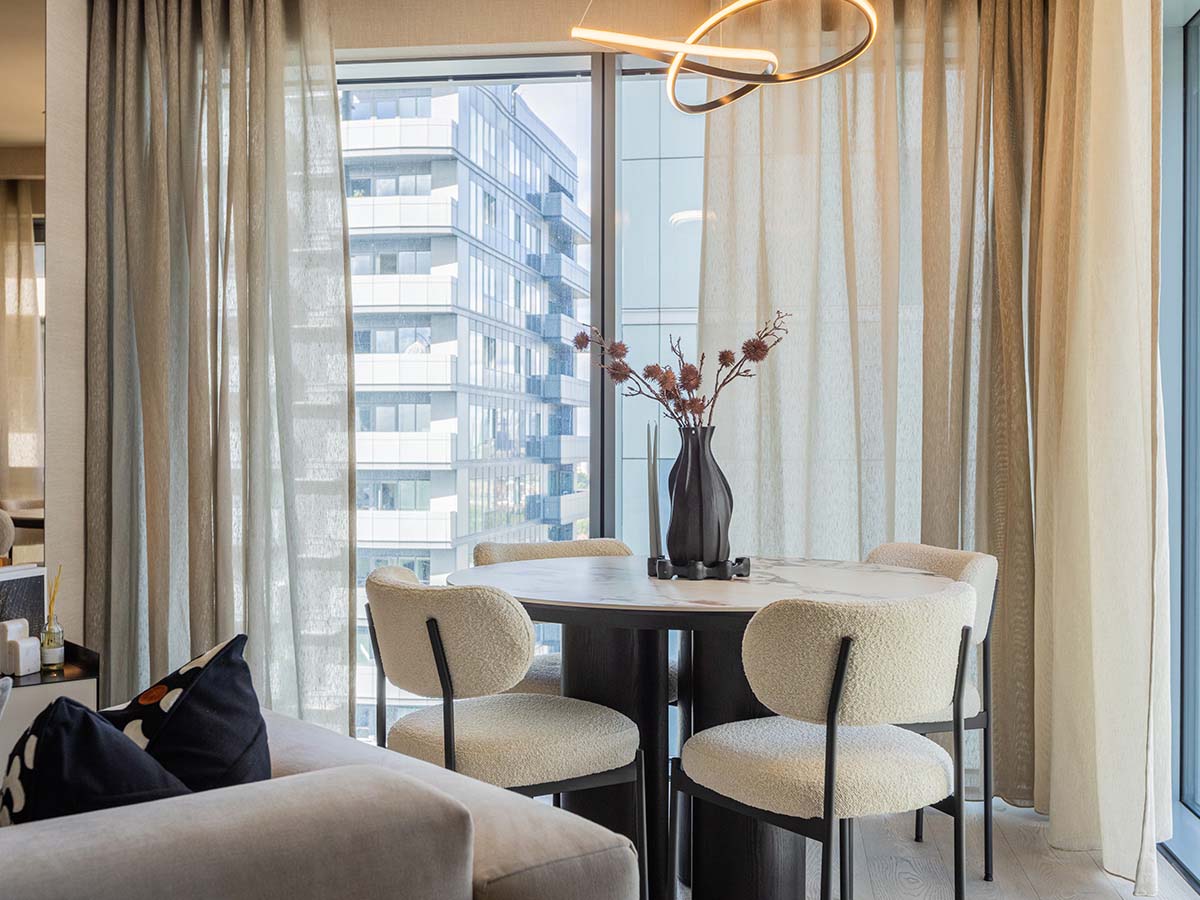 A modern round dining table at the Aspen project, surrounded by stylish boucle chairs and positioned under a contemporary halo chandelier