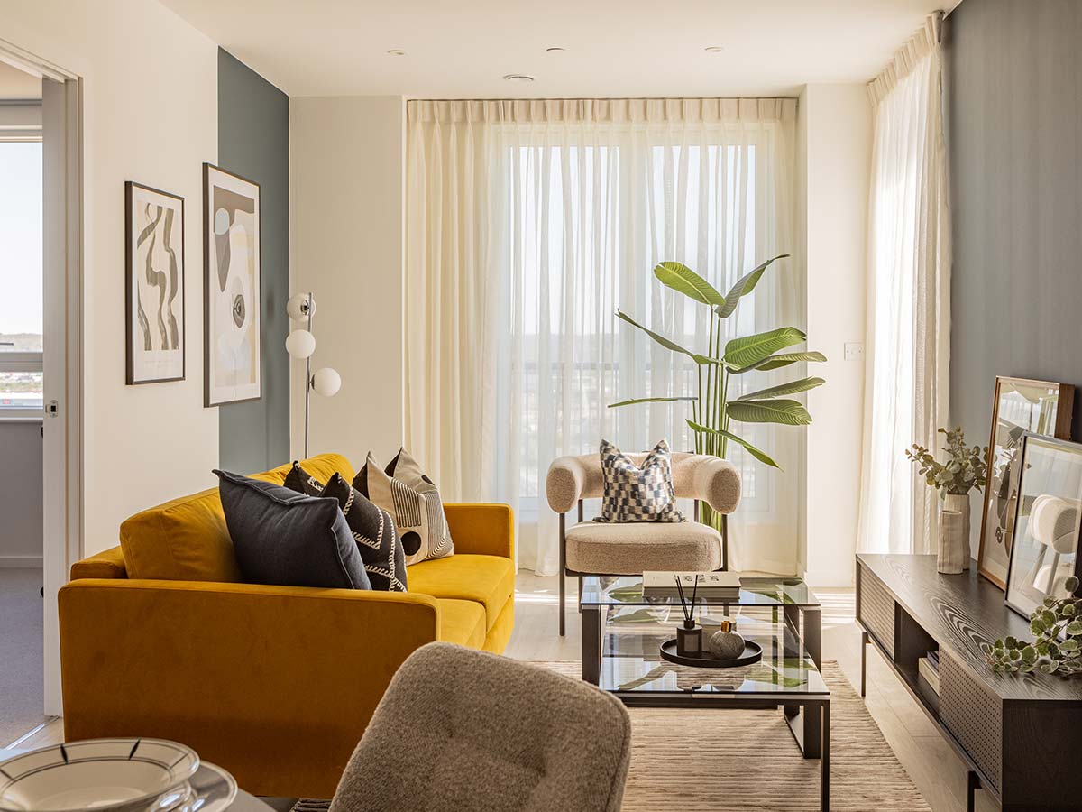A bright, modern apartment furnished with a complete turnkey furniture package for landlords, featuring a durable and stylish yellow sofa and dark grey accent wall