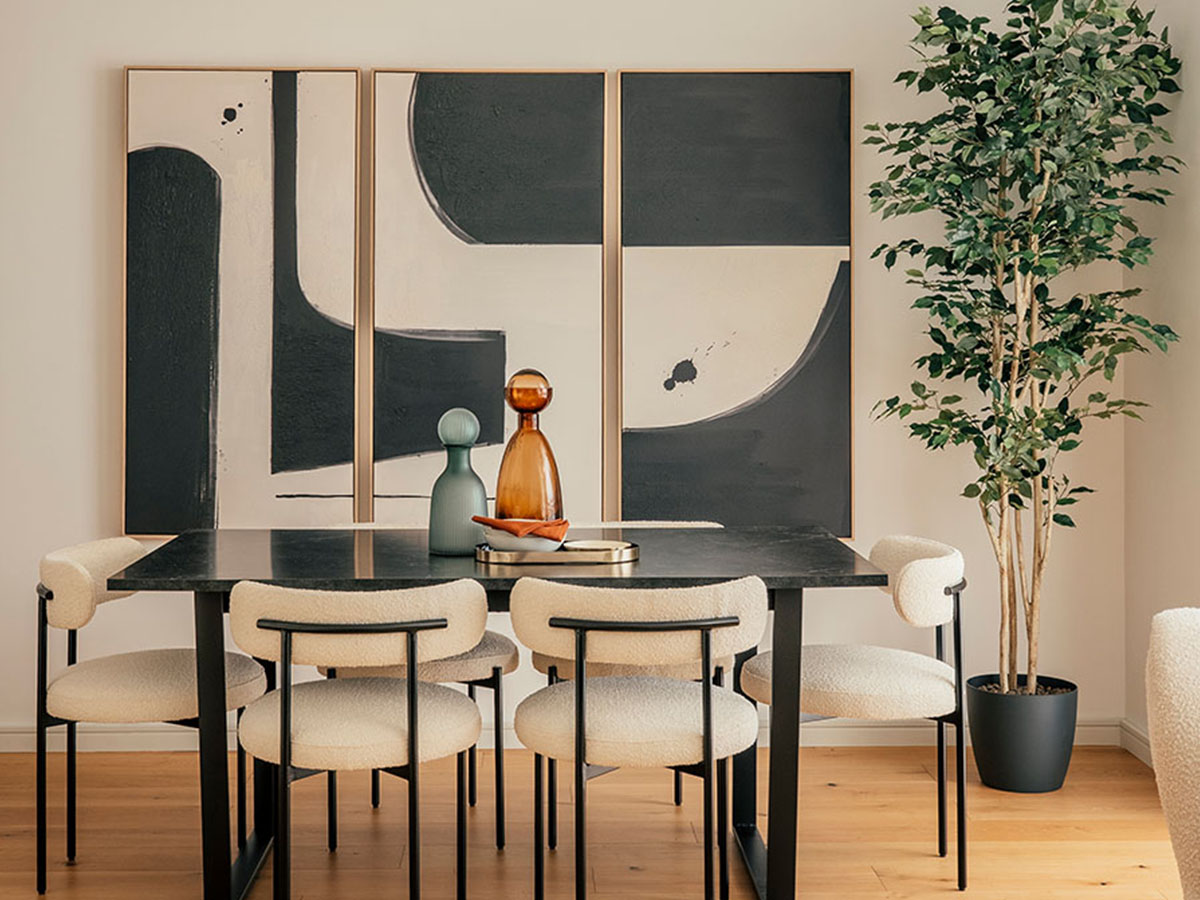 A modern dining room at 804 Riverside featuring a black table, white boucle chairs, and a large three-panel abstract art installation on the wall
