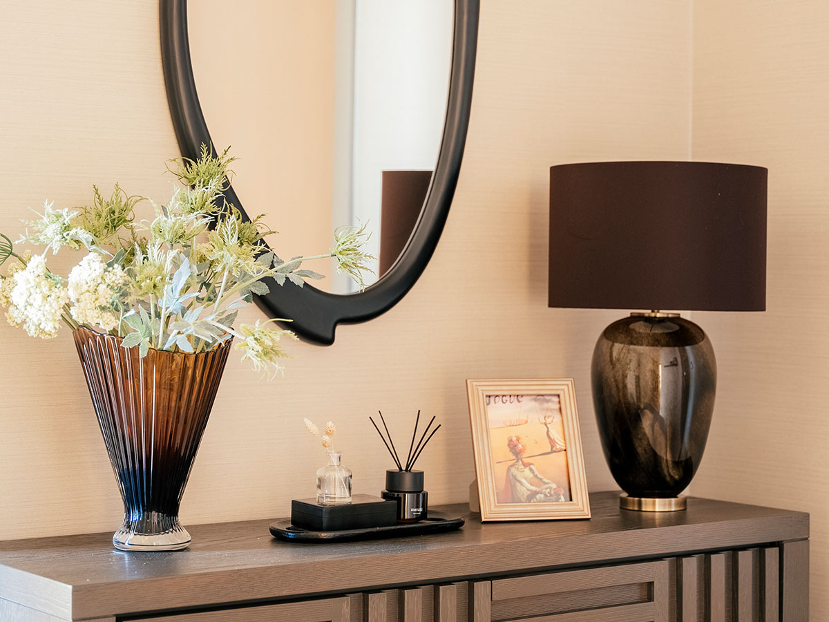 A round glass coffee table styled with a wooden chess set, white hydrangeas in a green vase, and luxury coffee table books in a London living room