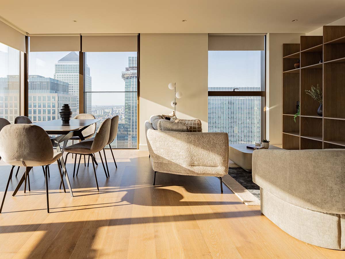 Bright open-plan apartment interior by InStyle Direct showing a luxury dining area and living room with hardwood floors, bathed in natural sunlight with views of the London skyline
