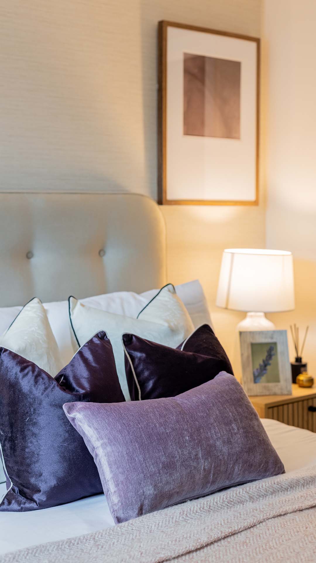 A cozy bedroom with pillows on a bed and soft lighting.