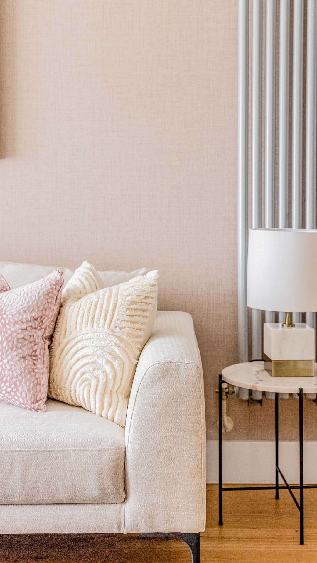 Close-up of cozy sofa with textured cushions and side table lamp in neutral interior