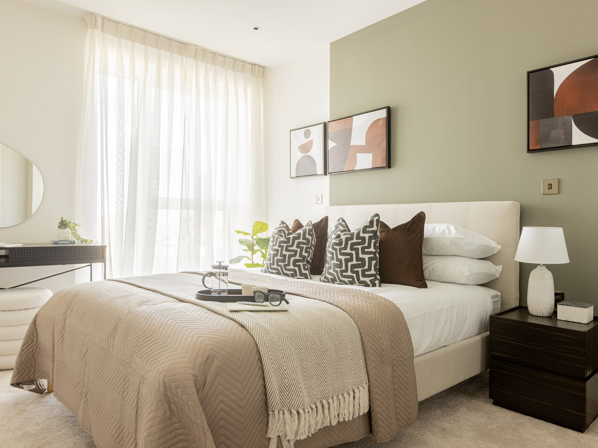 A complete master bedroom furniture package by InStyle Direct featuring a cream upholstered bed, olive green feature wall, abstract art, and dark wood bedside tables in White City