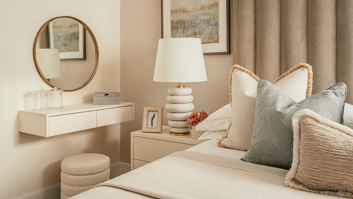 Modern bedroom with vanity desk, round mirror, bedside lamp, and neutral soft furnishings