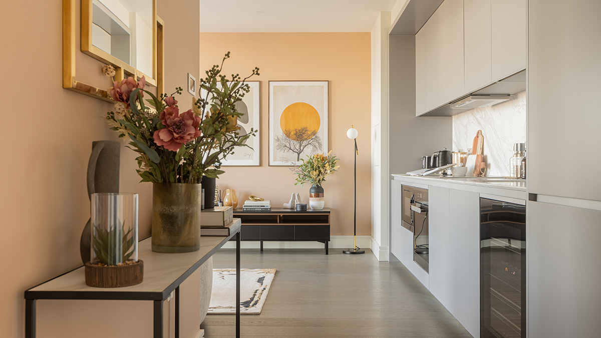 Modern kitchen and hallway with styled console table, floral decor and built-in appliances in a London apartment at One Bishopsgate Plaza