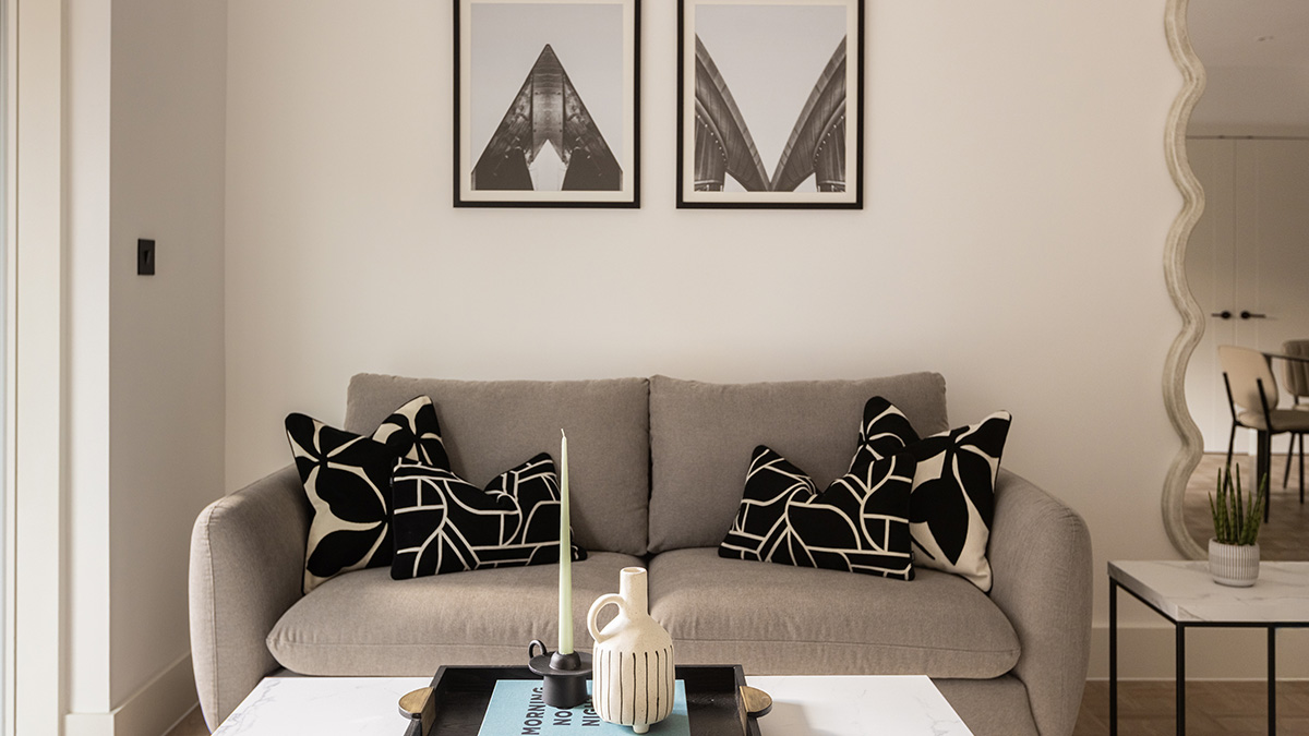 Modern living room interior at Cavendish House Beaufort Park London featuring neutral sofa, patterned cushions, and wall artwork.