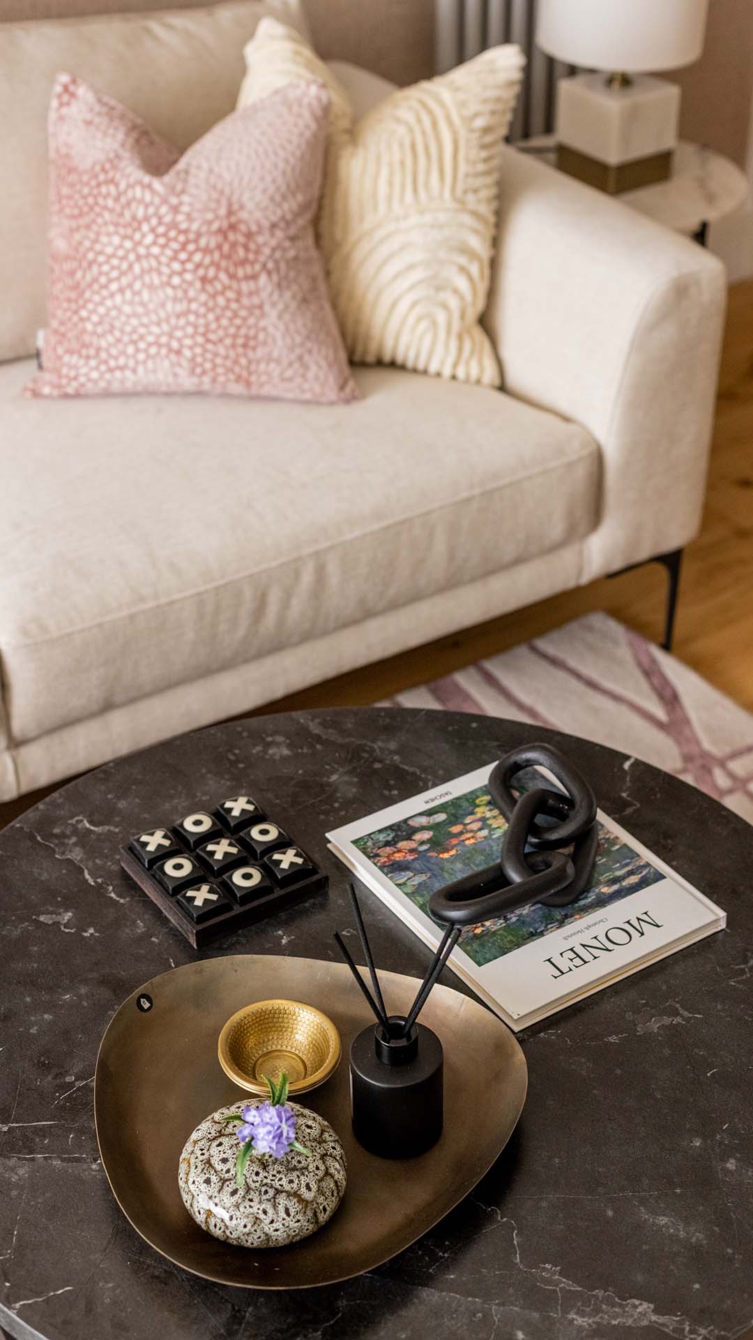 A living room with a light-colored couch, decorative pillows, and a marble coffee table.