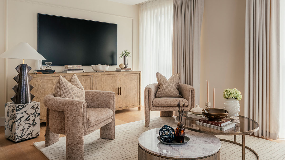 Modern living room with TV unit, upholstered armchairs, wooden console, and styled coffee table
