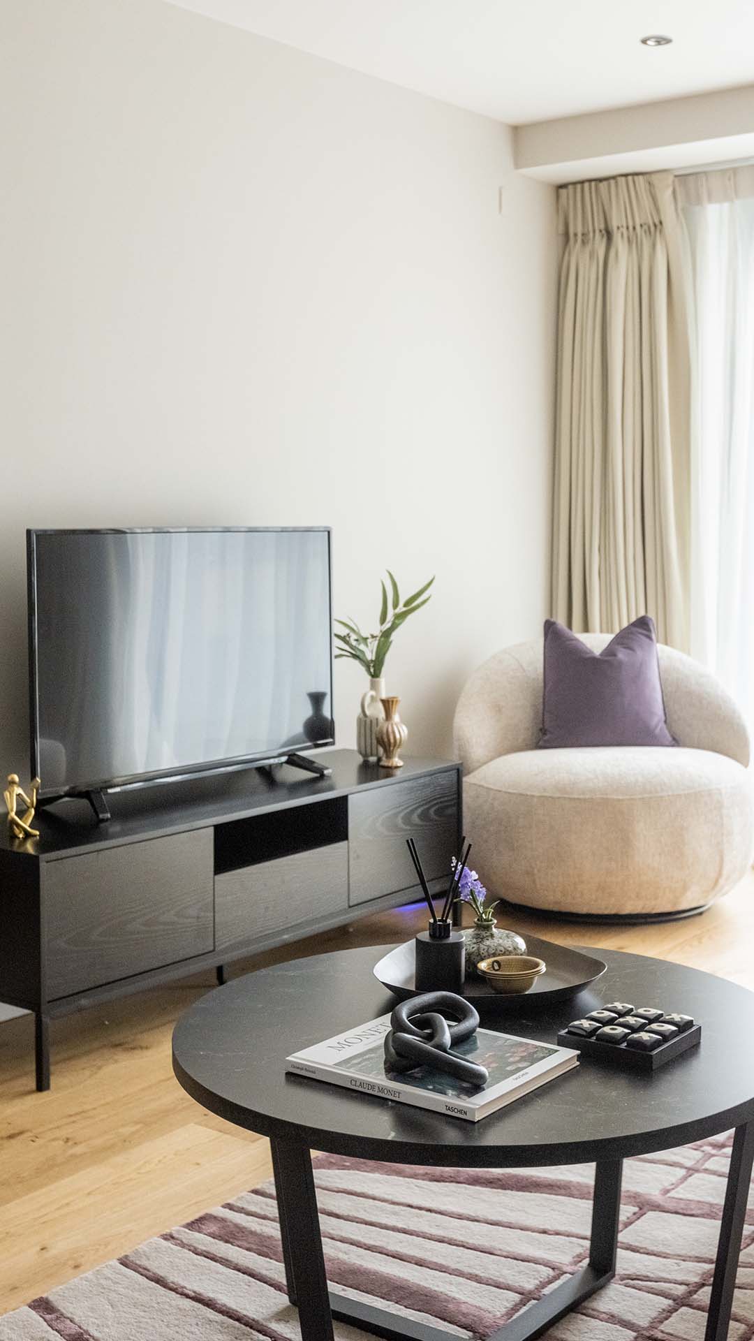 Modern neutral living room with TV console, round armchair, and minimalist decor