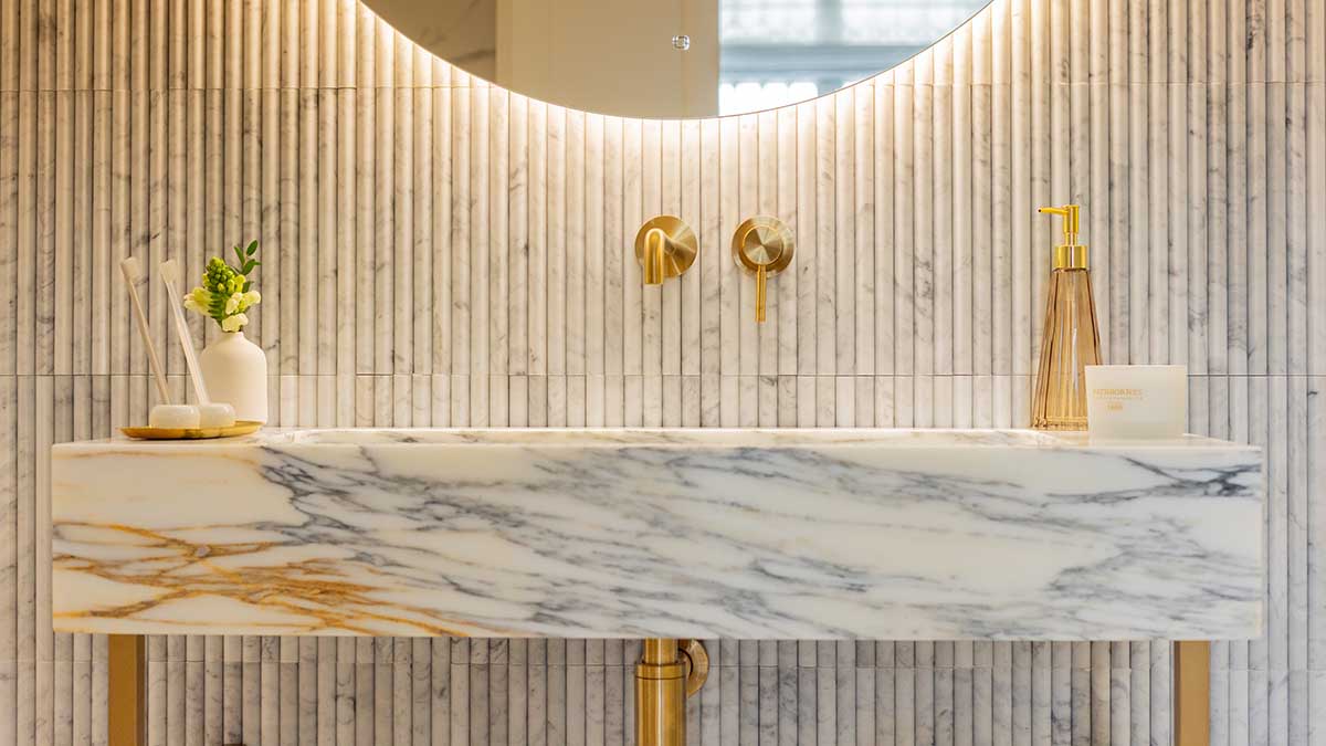 Close-up of marble vanity with gold taps and warm lighting