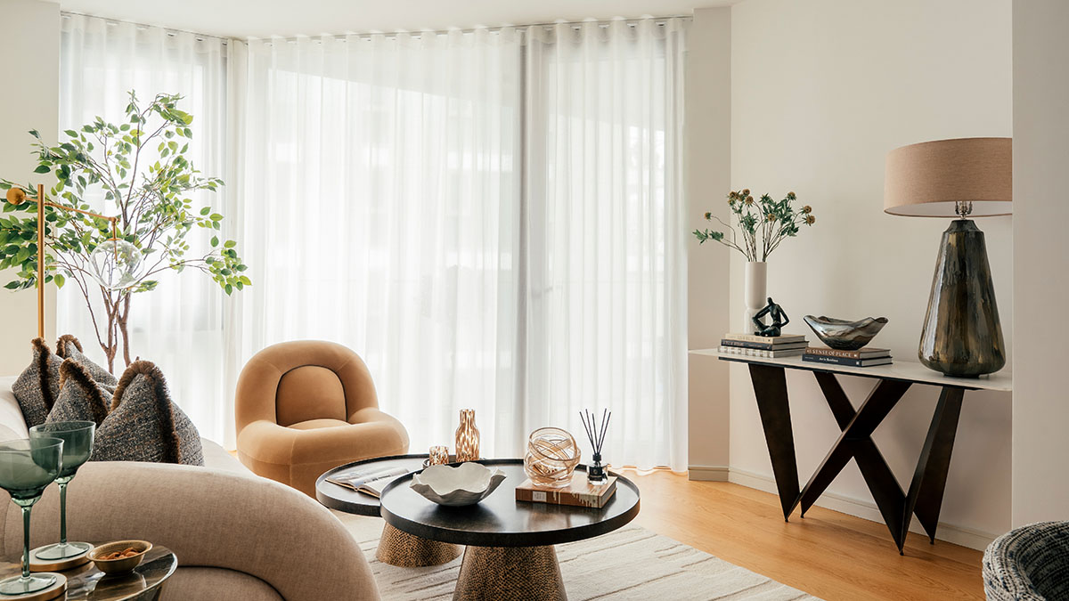 Contemporary living room with sheer curtains, accent chair, round coffee table and styled console table
