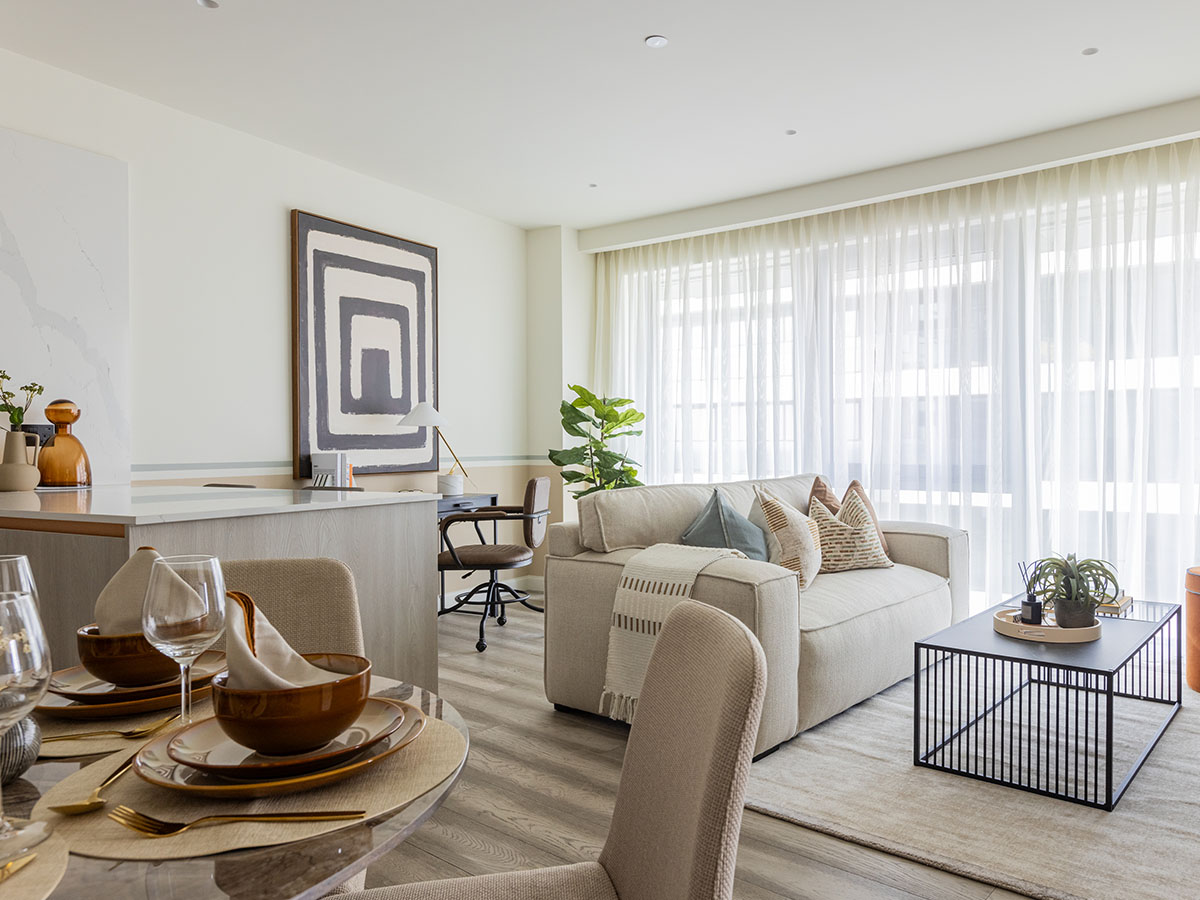A luxury bedroom corner styled by InStyle Direct featuring a neutral upholstered headboard, symmetrical brass bedside lamps, and a series of framed abstract art pieces in earthy tones in Canary Wharf.