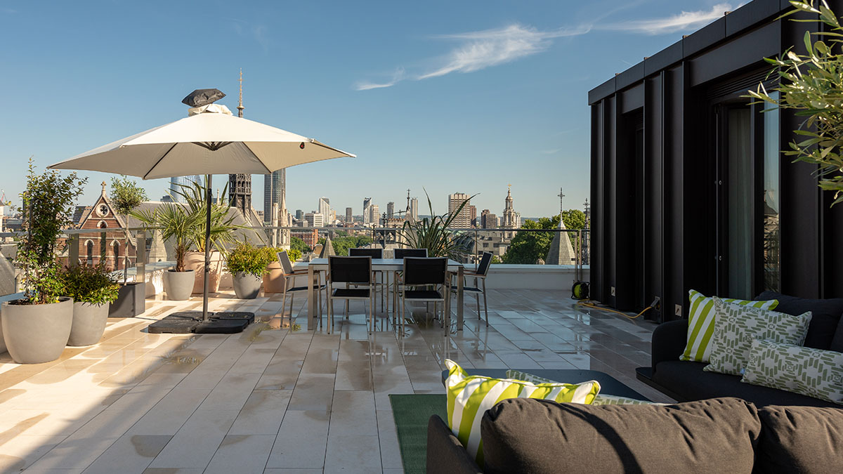 Modern apartment terrace with outdoor seating, cushions and sunlit wooden flooring