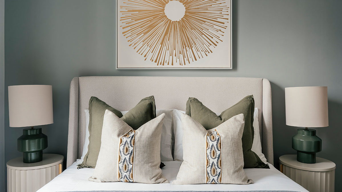 Modern bedroom with sunburst wall art, upholstered headboard, green cushions, and bedside lamps