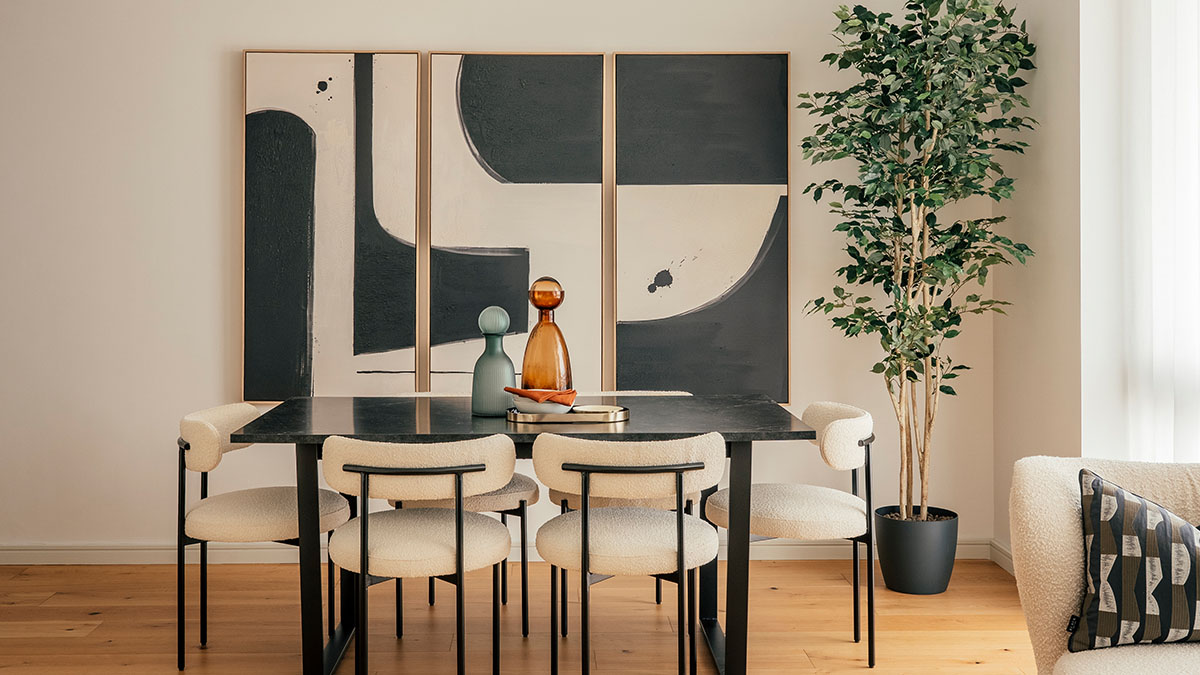 Modern dining room with abstract wall art, neutral upholstered chairs, black table, and indoor plant