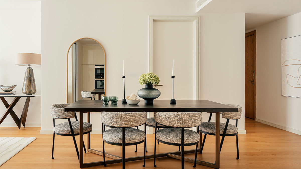 Modern dining room in a styled apartment with dark wood table, upholstered chairs and neutral interior design