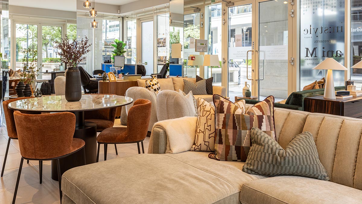 Elegant furniture showroom featuring marble dining table, brown upholstered chairs, and modern living room décor