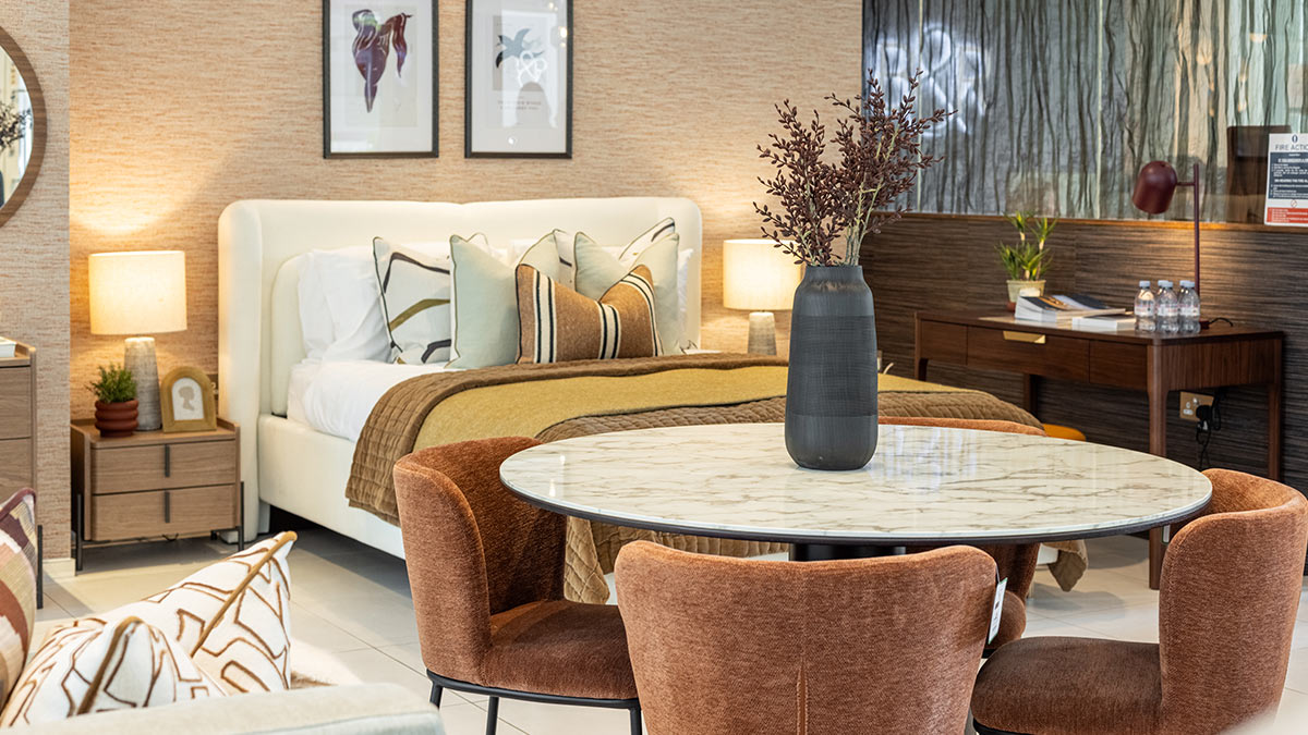 Luxury studio apartment interior with marble dining table, upholstered chairs, modern bed and warm-toned furniture package.