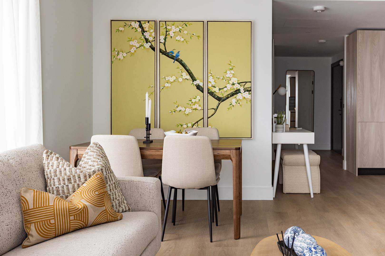 Modern open-plan dining area with wooden table, cream chairs, floral wall art and neutral-toned interior at Regents View apartment.