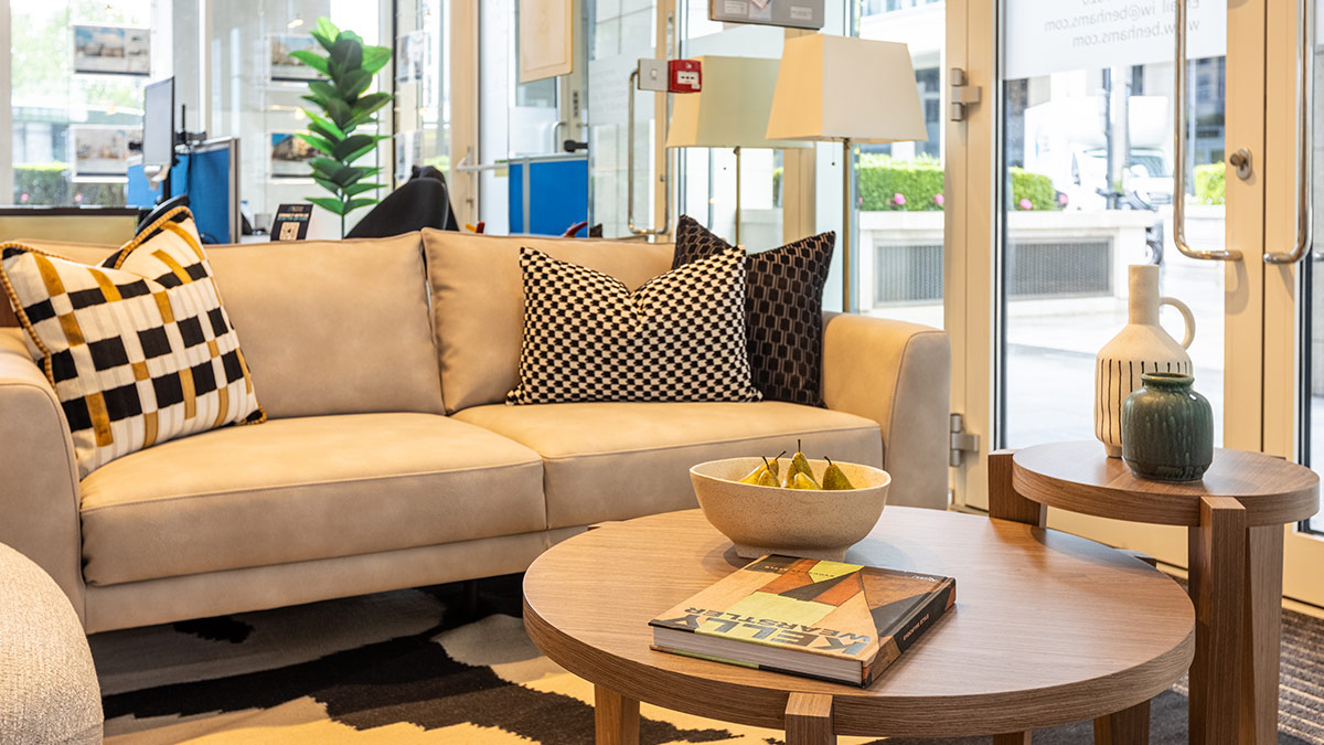 Contemporary showroom interior with beige sofa, patterned cushions, and round wooden coffee table styling