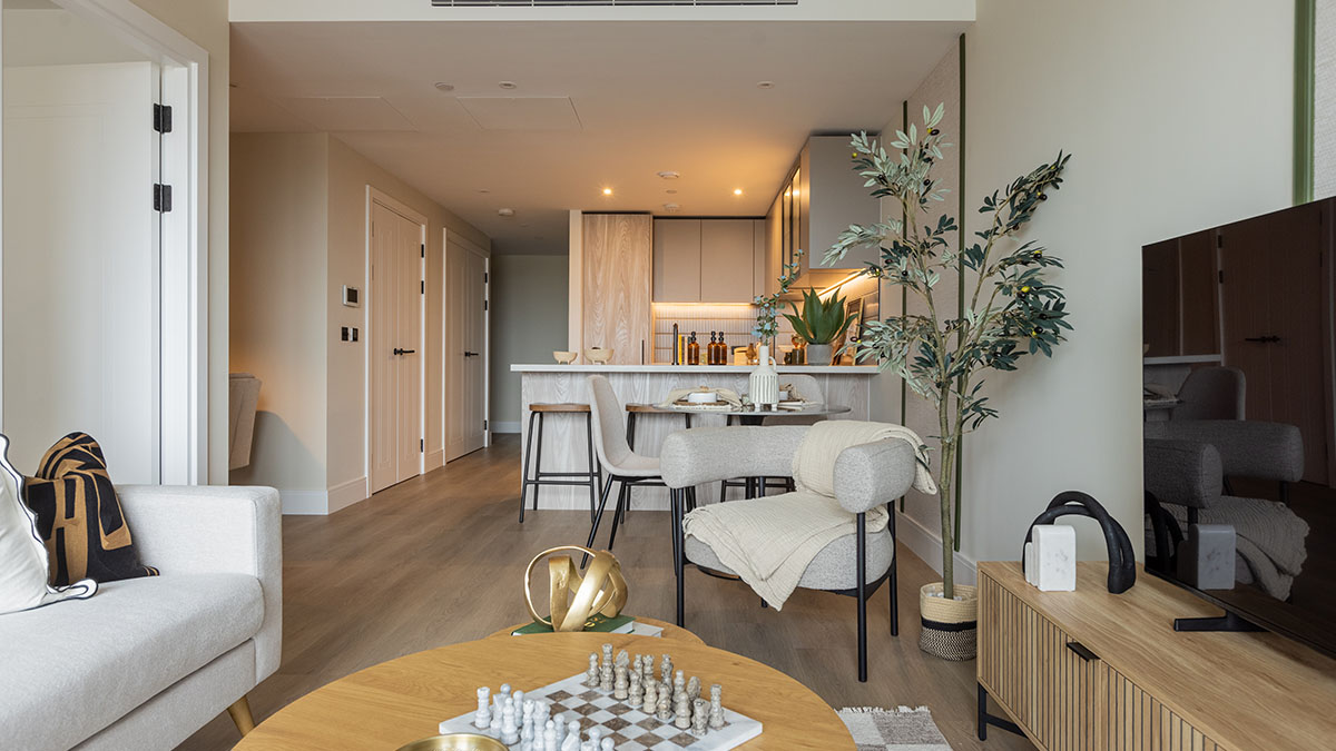 Modern open-plan living room and kitchen interior at Regents View featuring neutral furnishings, wooden flooring, dining area, and contemporary décor.