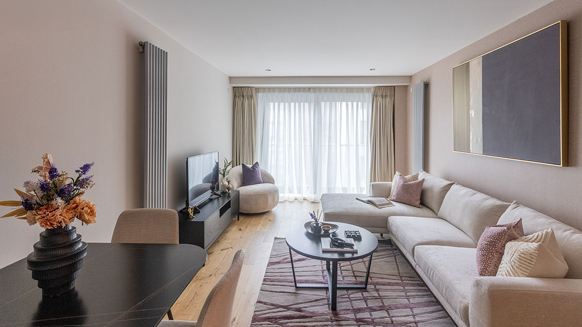 Modern open-plan living room with beige sectional sofa, black dining table, round coffee table and floor-to-ceiling curtains.