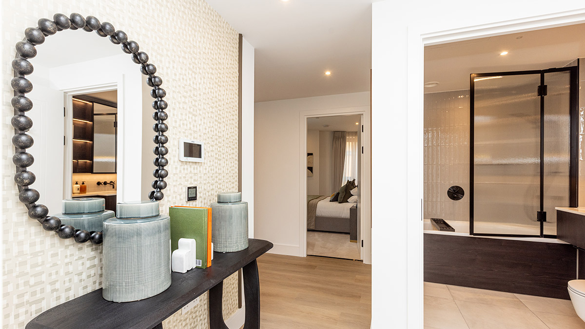 Modern apartment hallway featuring a designer console table, decorative round mirror, and views into the bathroom and bedroom.