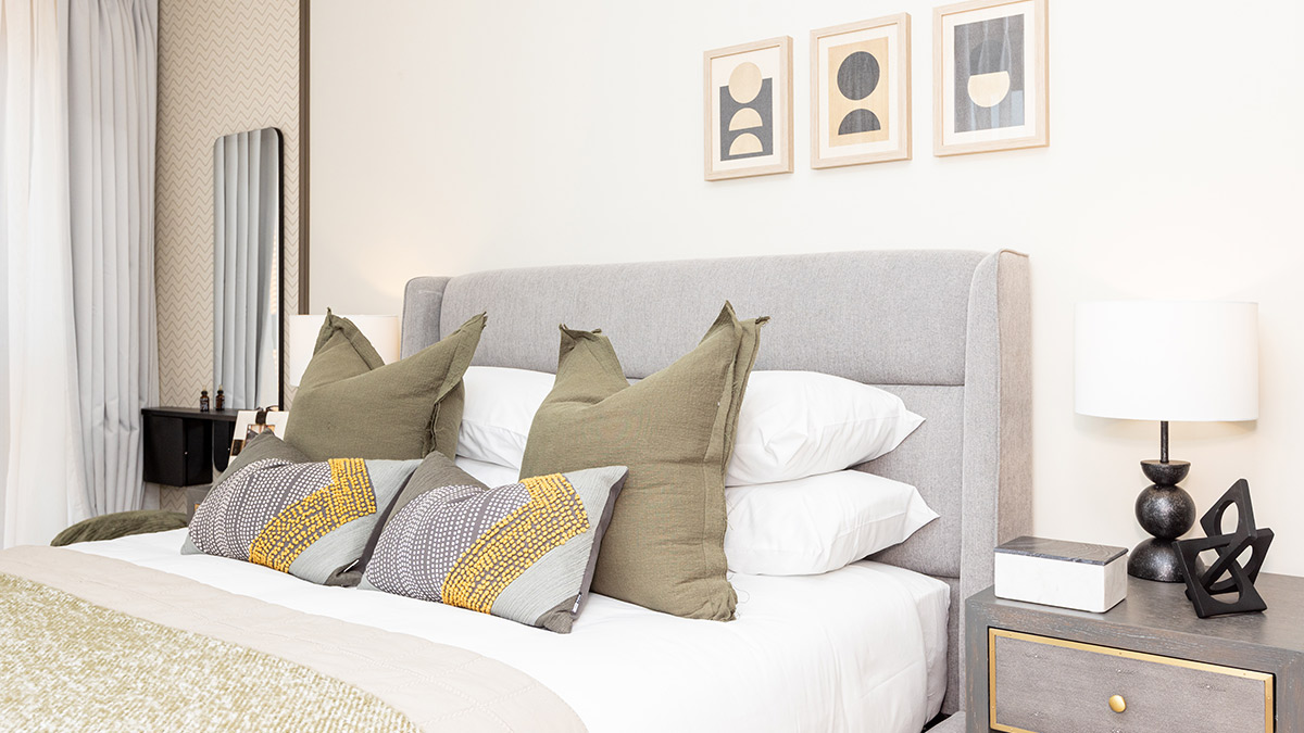 Stylish bedroom with an upholstered bed, neutral bedding, decorative cushions, and contemporary bedside tables.