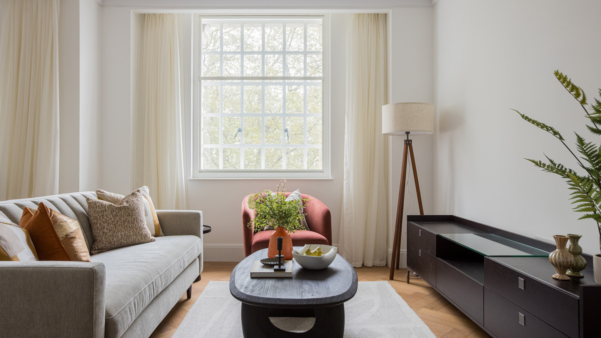 Bright living room with large sash window, designer sofa and modern furniture in a furnished Millbank SW1P apartment.