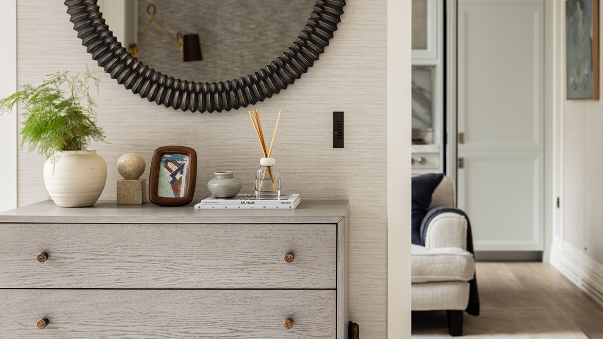 Designer console table with decorative accessories, round statement mirror and indoor plant in a luxury London apartment entrance.