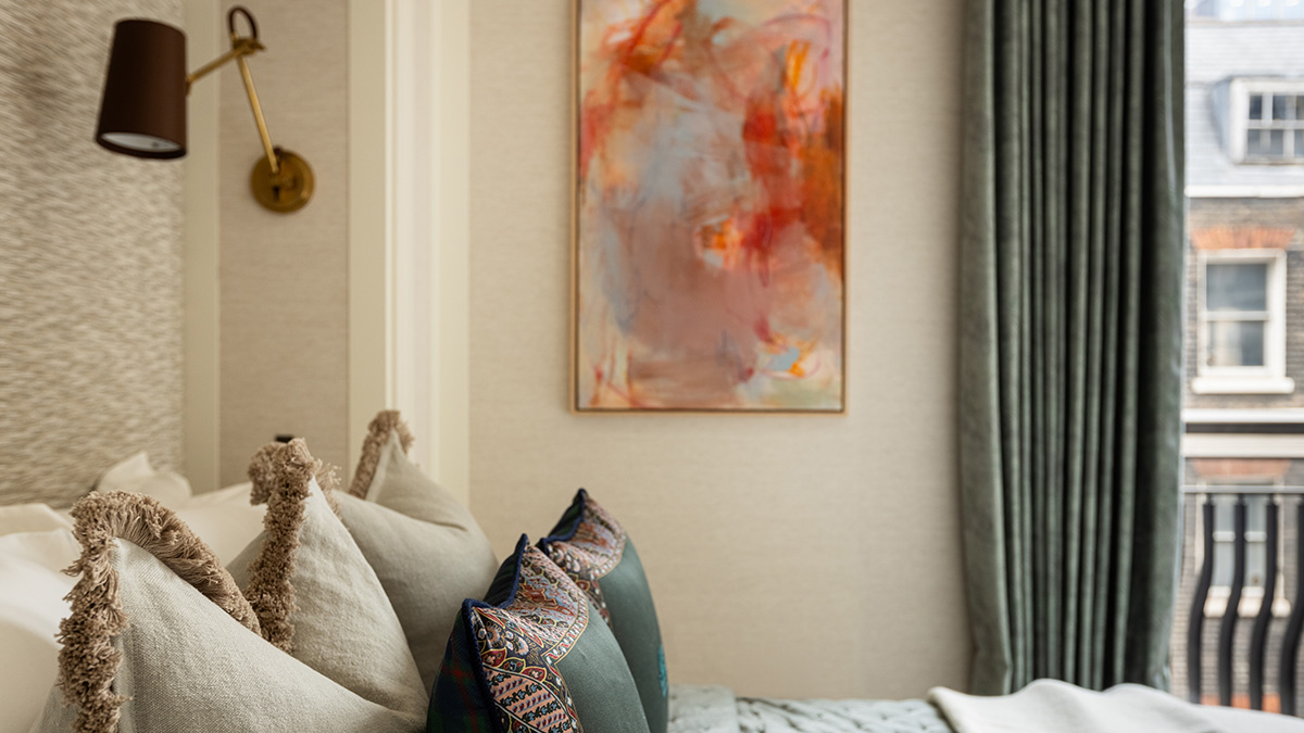 Luxury bedroom featuring designer cushions, abstract wall art, brass reading light and floor-to-ceiling curtains in a London apartment.