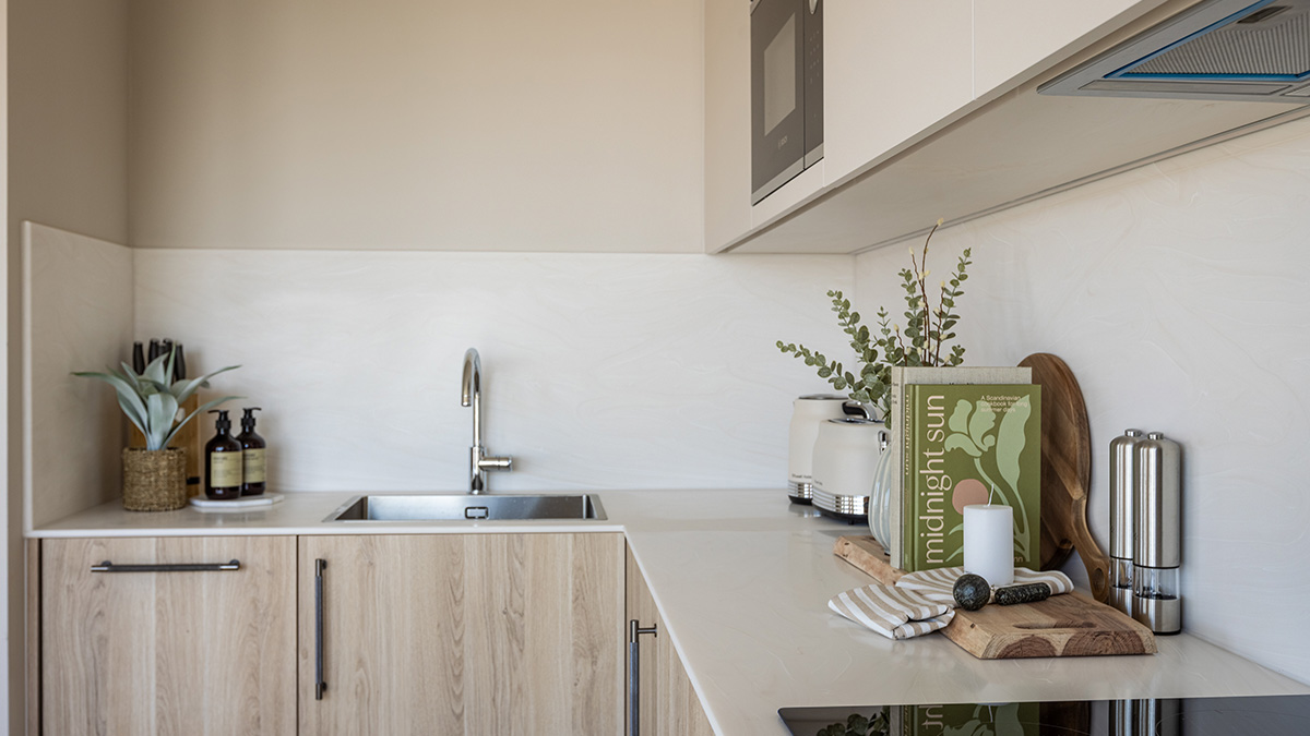 Modern minimalist kitchen with wood-finish cabinets, integrated appliances, quartz worktops, and stylish countertop accessories.