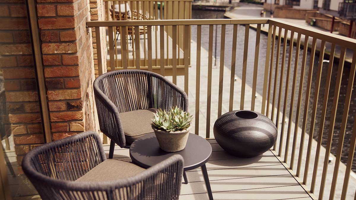BTR apartment balcony with outdoor lounge chairs, a round table, decorative planter and contemporary outdoor furniture.
