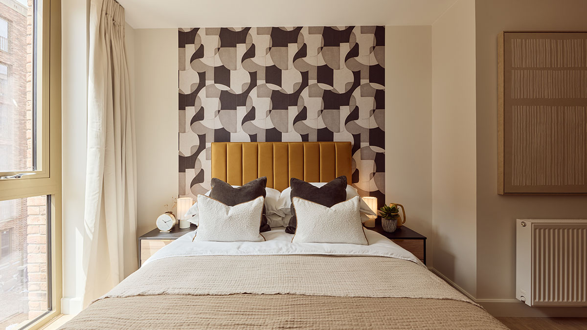 Elegant bedroom with a mustard velvet headboard, geometric feature wall and luxury bedding.