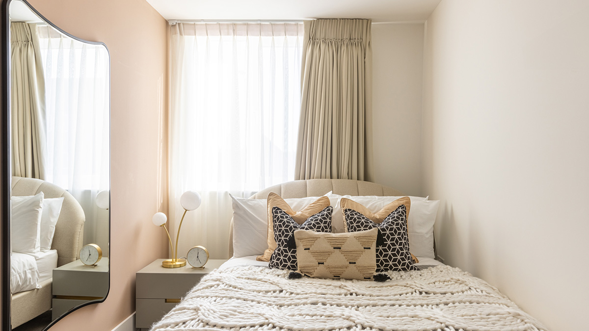 Contemporary bedroom with upholstered bed, patterned cushions and full-height curtains in Watford